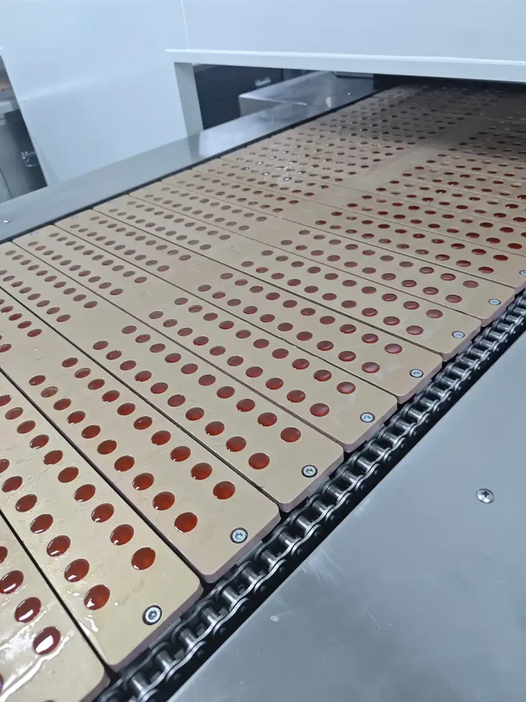 The gummy syrup is deposited into molds of various shapes